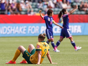 Australia's Larissa Crummer sits on the pitch as Japan celebrates its quarterfinal win (Ian Kucerak, Edmonton Sun).