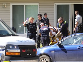 Grande Prairie Fire Department firefighters, EMS paramedics and Grande Prairie RCMP officers wheel out a patient of an apartment during a shooting incident at Avondale Manor on 107 Avenue near 100 Street on Saturday. Alexa Huffman/Grande Prairie Daily Herald-Tribune/Postmedia Network