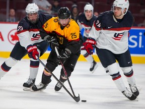 (25) Fabio Pfohl (F) battles for the puck against (23) Zach Werenski (D) and (24) Anthony DeAngelo (D) in the first period of the game between Team USA and Team Germany during the 2015 IIHF World Junior Championship on December 28, 2014 at the Bell Centre in Montreal, QC. JOHANY JUTRAS / LE JOURNAL DE MONTREAL / AGENCE QMI.