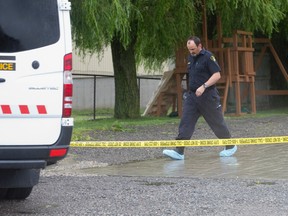 An OPP forensic identification officer walks away from a Westminster Drive home, where owner Robert St. Denis, 51, was found dead Thursday morning, southeast of London, Ont. on Sunday June 28, 2015. Police are continuing their investigation after deeming the incident a homicide.  Westminster Drive between Westchester Bourne and Old Victoria Road is expected to be closed through Tuesday morning, according to police.  Craig Glover/The London Free Press/Postmedia Network