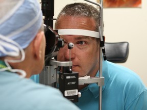 Dr. Ian MacDonald (left) gives Ken Ross (right) an eye exam at the Royal Alexandra Hospital in Edmonton on June 29, 2015. Ross was the first Canadian patient to receive gene therapy treatment for choroideremia, a genetic degenerative eye disorder that eventually causes blindness. Claire Theobald/Edmonton Sun
