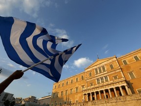 A protester waves a Greek flag during an anti-austerity rally in Athens, Greece, June 29, 2015. Stunned Greeks faced shuttered banks, long supermarkets lines and overwhelming uncertainty on Monday as a breakdown in talks between Athens and its international creditors plunged the country deep into crisis. REUTERS/Yannis Behrakis