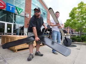 Sycamore Energy Inc. construction project manager Jeff Mortimer, left, and president Justin Phillips, right, piece together a solar powered phone charging station, the first in Canada and one of two now in the downtown core, outside of the Covent Garden Market. The charging station, which has outlets for Blackberry, Android, and iPhone smartphones, stores energy in enclosed batteries, allowing the power station to be used 24/7. (CRAIG GLOVER, The London Free Press)