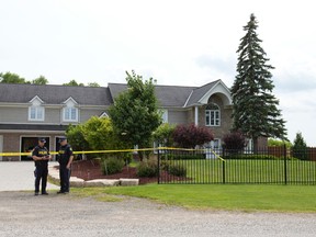 OPP Constables Doug Graham, left, and Jamie Thomas look over notes outside of a Westminster Drive home, where police have been investigating a death of Robert St. Denis, 51. (CRAIG GLOVER, The London Free Press)