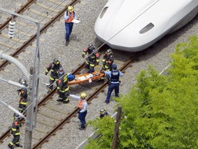A passenger on the stretcher is carried by rescue workers from a Shinkansen bullet train after it made an emergency stop in Odawara, south of Tokyo, in this aerial view photo taken by Kyodo June 30, 2015. A Japanese Shinkansen bullet train made an emergency stop on Tuesday and a passenger was found at the entrance of a carriage covered in flammable liquid, officials said. Media reports said a man in his 30s had set himself on fire. Two people were reported to be in cardiac arrest after smoke was detected on the train, which was bound for the western city of Osaka from Tokyo. Mandatory credit REUTERS/Kyodo