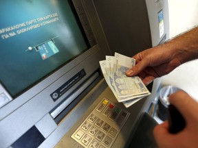 A man withdraws sixty Euros, the maximum amount allowed after the imposed capital controls in Greek banks, at a National Bank of Greece ATM on June 30. (REUTERS/Yannis Behrakis)