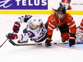 Canada’s Meaghan Mikkelson (right) and Alex Carpenter of the U.S. battle for the puck during hockey action at the Air Canada Centre in Toronto Monday December 30, 2013. (Ernest Doroszuk/Toronto Sun/Postmedia Network)