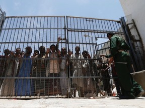 Inmates stand behind the gate at the entrance of the central prison in Sanaa, Yemen in this May 26, 2014 file photo. Roughly 1,200 prisoners have escaped in a series of prison breaks. REUTERS/Khaled Abdullah