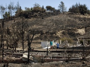 Broadview neighbourhood residents Mandy Stirling and her son Carson Stirling, 5, walk through the remains of their neighbours' homes that were consumed by the Sleepy Hollow fire in Wenatchee, Washington June 30, 2015. A wildfire burning unchecked in Washington state has destroyed at least 23 homes and three commercial buildings near the eastern foothills of the Cascades, state police and emergency management officials said on Monday.  REUTERS/David Ryder