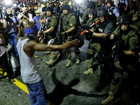 In this  Aug. 9, 2014 file photo, police arrest a man as they disperse a protest in Ferguson, Mo. Police antagonized crowds gathered to protest the shooting of 18-year-old Michael Brown in Ferguson, violated free-speech rights and made it difficult to hold officers accountable, according to a U.S. Department of Justice report on Tuesday, June 30, 2015. AP Photo/Charlie Riedel/File