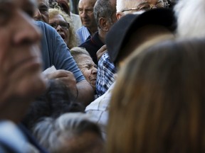 A pensioner, centre, is squeezed as she waits outside a National Bank branch to receive part of her pension in Athens, Greece, on July 1, 2015. (REUTERS/Alkis Konstantinidis)