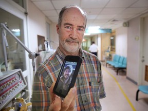 Standing outside of the intensive care unit at a local hospital, Roger Haas, of Mont Vernon, N.H., holds an iPhone photo of his son Alex Haas, 26, seriously burned in Saturday's accidental water park fire in Taipei, Taiwan, on July 1, 2015. (AP Photo/Wally Santana)