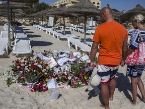 Tourists pay their respects in front of a makeshift memorial at the beach near the Imperial Marhaba resort, which was attacked by a gunman in Sousse, Tunisia, June 29, 2015. The gunman disguised as a tourist opened fire at the Tunisian hotel last Friday with a rifle he had hidden in an umbrella, killing 39 people including Britons, Germans and Belgians as they lounged at the beach in an attack claimed by Islamic State.  REUTERS/Zohra Bensemra
