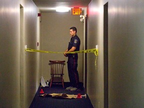 A police officer stands outside the apartment where a woman was stabbed to death. (Free Press file photo)