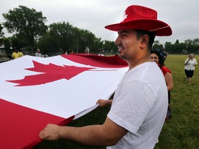Jihad Ahmed help carry a giant Canadian flag at the 18th annual NorQuest College Canada Day celebrations in Edmonton, Alberta Tuesday, June 30, 2015. Perry Mah/Edmonton Sun/Postmedia Network