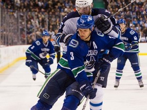 Kevin Bieksa #3 of the Vancouver Canucks tries to control the loose puck while being pressured by Andrew Ladd #16 of the Winnipeg Jets in NHL action on March, 24, 2015 at Rogers Arena in Vancouver, British Columbia, Canada.   Rich Lam/Getty Images/AFP== FOR NEWSPAPERS, INTERNET, TELCOS & TELEVISION USE ONLY ==