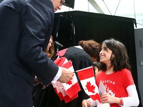 Aya Dhia Mounir, 8, is given a flag from MP John Carmichael during a citizenship ceremony at Harbourfront Centre on Wednesday July 1, 2015. (Dave Abel/Toronto Sun)