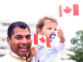 Dr. Suman Koka and his son Ronan march into the Sudbury Community Arena for the Sudbury Multicultural and Folk Arts Association's celebration of Canada's 148th birthday in Sudbury, Ont. on Wednesday July 1, 2015. Gino Donato/Sudbury Star/Postmedia Network