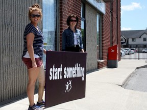 SARAH HYATT/THE INTELLIGENCER
Mentoring co-ordinator Kylie Caume (right) and executive director Arlene Coculuzzi of Big Brothers and Big Sisters Hastings and Prince Edward Counties hold a Start Something sign outside the organization’s new location in Belleville. The new Big Brothers, Big Sisters office is located at 55 Pinnacle St. South.