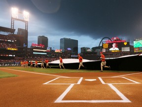 St. Louis Cardinals grounds keepers cover the infield with a tarp as rain begins to fall after the scheduled start time for a game between the St. Louis Cardinals and the Chicago White Sox on July 1, 2015, at Busch Stadium. (Chris Lee/St. Louis Post-Dipatch via AP)