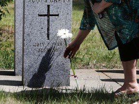 Eve Bassett lays a flower on her father's headstone during a memorial for Malcom Jack, the last EPS officer to receive a regimental funeral before Ezio Faraone at Westlawn Cemetery in Edmonton, Alberta on Thursday, July 2, 2015.  Perry Mah/Edmonton Sun
