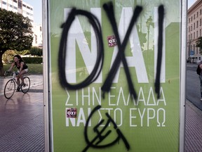 People make their way  past a ' YES to greece, yes to Euro ' poster sprayed with a graffiti reading ' NO'  refering to upcoming controversial referendum in Athens  on July 2, 2015 .Greece's government and international creditors raised the stakes on July 2 over a weekend referendum seen as decisive for the nearly insolvent EU country's political and financial future. While Prime Minister Alexis Tsipras has urged Greeks to vote 'No' to the austerity measures demanded by international creditors, opposition parties including the centre-right New Democracy are campaigning for a 'Yes' vote in the referendum on July 5.  AFP PHOTO / Louisa Gouliamaki