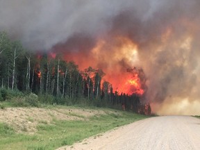 Forest fires throw flames above a tree-line along highway 969 in southern Saskatchewan on June 29, 2015. Saskatchewan Premier Brad Wall says the province has spent its firefighting budget for the year. The Premier says he's not worried about money right now and the government's priority is to keep fighting wildfires in the north. THE CANADIAN PRESS/HO - Saskatchewan Ministry of Highways and Infrastructure