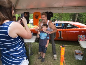 Jacquie George takes a photo of her six year old son Morgan with "Dukes of Hazzard" star John Schneider in front of the TV show's icon car "General Lee" at the Fleetwood Country Cruize-in in London, Ont. on Sunday June 7, 2015. Thousands of people attended the annual car show on the Steve Plunkett estate. Derek Ruttan/The London Free Press/Postmedia Network