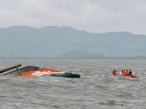 Rescuers search for survivors next to the haul of the ill-fated ferry (L) after it capsized near the pier the day before in the central Philippine city of Ormoc, on July 3, 2015. The ferry loaded with nearly 200 people capsized off the central Philippine port on July 2, officials said, killing at least 38 people in the latest of the country's long string of maritime tragedies.    AFP PHOTO / Lito Bagunas