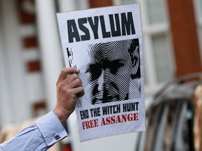 A supporter of Wikileaks founder Julian Assange holds a placard during a gathering outside the Ecuador embassy in London, Britain June 19, 2015. REUTERS/Stefan Wermuth
