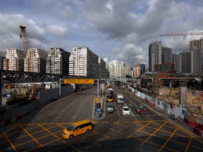 Cars travel down a road between blocks of 45-year-old residential flats, left, and the latest luxury homes, right, near the construction site for a high-speed railway, in West Kowloon, Hong Kong, on July 2, 2015. (REUTERS/Bobby Yip)