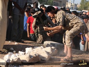 In this image posted on a militant website by the Aleppo branch of the Islamic State group on Friday, July 3, 2015, which has been verified and is consistent with other AP reporting, a militant smashes items that the group claims are smuggled archaeological pieces from the historic central town of Palmyra, Syria. An IS statement says the busts were found when the smuggler was stopped at a checkpoint and was later referred to an Islamic which ordered that they be destroyed and the man be whipped. (militant website via AP)