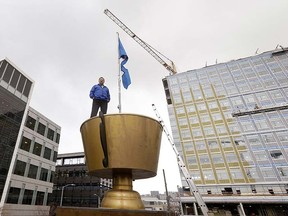 In this photo taken Feb. 26, 2015, Monty Holmes poses atop a giant trophy on the roof of his family-owned trophy shop and in view of new construction all around him, one of the few remaining enterprises from South Lake Union’s days as a blue-collar neighbourhood in Seattle. (AP Photo/Elaine Thompson)