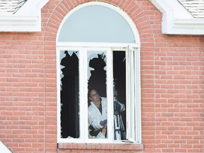 A crime scene investigator surveys the inside of a home in Boucherville, Que., on Friday, July 1, 2015, where the bodies of three men were found. THE CANADIAN PRESS/Graham Hughes