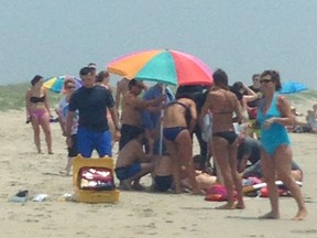 People surround and attend to a 68-year-old man that was bit by a shark in waist-deep water off Ocracoke Island, N.C., Wednesday, July 1, 2015. The man suffered wounds to his ribcage, lower leg, hip and both hands as he tried to fight off the shark. (Laura I. Hefty via AP)