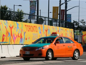 A Toronto cab passes by Pan Am signage near the Athletes' Village downtown on July 2, 2015. (Michael Peake/Toronto Sun)