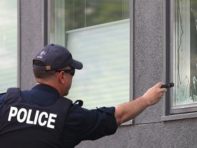 A Winnipeg Police officer shines a flashlight into a damaged window at the Petersen King law office on River Avenue after a bomb exploded there on Friday, seriously injuring a woman. (Kevin King/Winnipeg Sun)