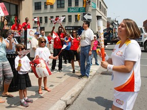 Angela McCann arrives for her leg of the Pan Am Torch Relay outside the CIBC at Bagot and Brock streets on Friday. McCann's parents, sisters and daughters were on hand to cheer her on as she became one of the 3,000 participants in the relay, which had a two-day stop in Kingston. (Julia McKay/The  Whig-Standard)