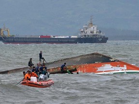 Rescuers tie a rope at the capsized vessel MBCA Kim Nirvana to pull it towards the shore near a port in Ormoc city, central Philippines, July 3, 2015. REUTERS/Alan Kristofer Motus
