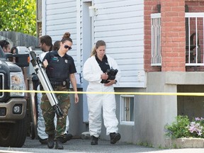 A crime scene investigator leaves a home in Boucherville, Que., on Friday, July 1, 2015, where the bodies of three men were found. THE CANADIAN PRESS/Graham Hughes