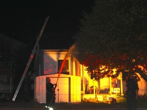 A firefighter works to extinguish a hot spot at a Brock Street fire late Saturday night. No one was injured though a neighbouring home was also evacuated. (MEGAN STACEY/Sentinel-Review)