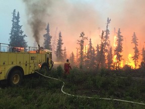 Firefighters tackle a wildfire near the town of La Ronge, Saskatchewan July 4, 2015 in a picture provided by the Saskatchewan Ministry of Government Relations. The Western Canadian province of Saskatchewan said on Sunday it was evacuating an additional 8,000 people from the far north of the province, as wildfires continue to spread and threaten homes. The provincial government said that as of Saturday there were 114 active fires in the province. More than 5,000 residents have already been moved out of the area in the past week. Picture taken July 4, 2015.  REUTERS/Saskatchewan Ministry of Government Relations/Handout via Reuters