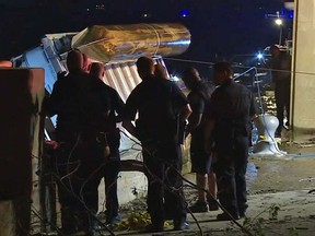 In this image taken from video, police officers look on as an overturned pontoon boat is pulled out of the water of the Ohio River Saturday, July 4, 2015, in Louisville, Ky. (Nathan Davis, WHAS-TV via AP)