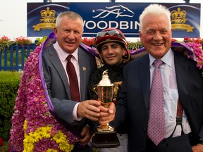 From left, Shaman Ghost trainer Brian Lynch, jockey Rafael Hernandez and owner Frank Stronach hold the Queen’s Plate trophy at Woodbine yesterday. (Michael Burns/photo)