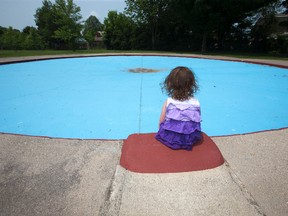 Three-year-old Lila Boyd sits at the edge of an empty wading pool at Smith Park in London, Ont. on Sunday. She has enjoyed cooling off at the pool the past two summers but this summer the city has been forced to close six wading pools due to a lack of life guards.Derek Ruttan/The London Free Press/Postmedia Network