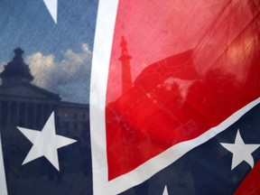 The South Carolina State House is seen through a Confederate flag held along Gervais Street, Monday, July 6, 2015, in Columbia, S.C. The South Carolina Senate voted Monday to remove the Confederate flag from a pole on the Statehouse grounds, though the proposal still needs approval from the state House and the governor. (Gerry Melendez/The State via AP)