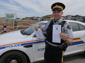 Const. Allan Peterson holds up one of the tickets he and members of the Chestermere RCMP are handing out to kids seen obeying traffic laws and doing good things in the city, east of Calgary, Alta. on Monday July 6, 2015.  Kids get a $5 gift certificate then entered in a draw for tickets for XFest. Stuart Dryden/Calgary Sun/Postmedia Network