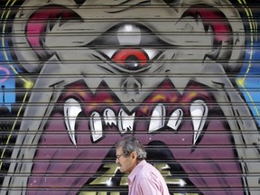 A man walks past graffiti painted on a closed shop at Monastiraki area in central Athens, Greece, July 7, 2015. Greece faces a last chance to stay in the euro zone on Tuesday when Prime Minister Alexis Tsipras puts proposals to an emergency euro zone summit after Greek voters resoundingly rejected the austerity terms of a defunct bailout. (REUTERS/Christian Hartmann)