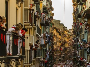 People watch as Jandilla fighting bulls and revelers run during the running of the bulls at the San Fermin festival, in Pamplona, Spain, Tuesday, July 7, 2015. Revelers from around the world arrive to Pamplona every year to take part in some of the eight days of the running of the bulls. AP Photo/Andres Kudacki