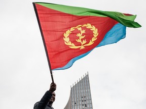 A man waves an Eritrean national flag as hundreds of Eritreans demonstrate in front of the African Union headquarters in support of the UN Inquiry report and asking for measures to be taken against Eritrea on June 26, 2015 in Addis Ababa. (AFP/Nichole Sobecki)